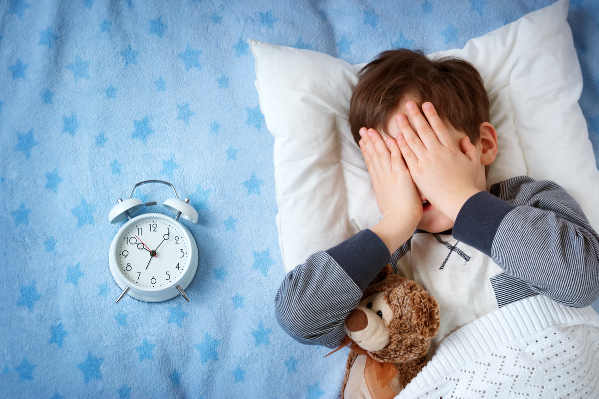 six years old child sleeping in bed with alarm clock