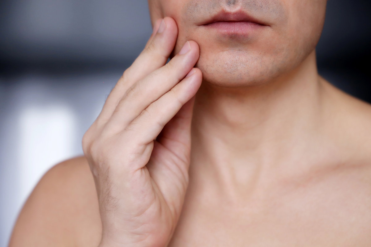 Shaved male face close up. Man touching his chin, beauty and skin care concept