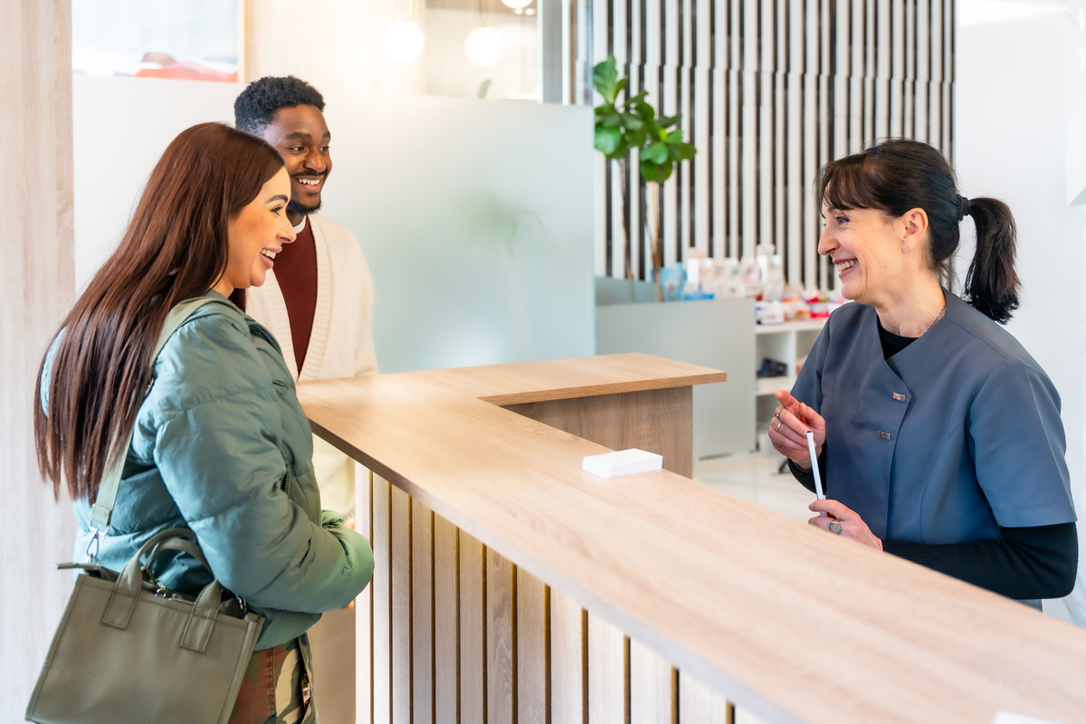 Couple smiling at receptionist in dental clinic
